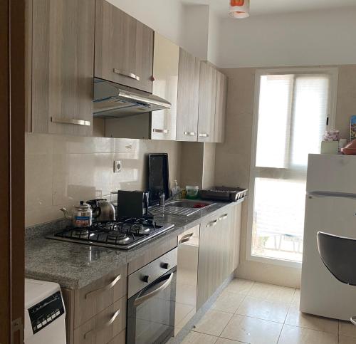 a kitchen with a stove top oven next to a refrigerator at Spacious appartement of two rooms close to morocco mall in Casablanca