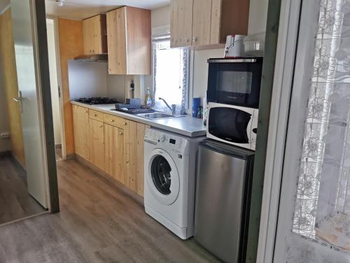 a kitchen with a washing machine and a microwave at Mobil-home in Foix