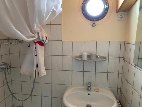 a bathroom with a sink and a shower curtain at Küstenmotorschiff Aventura in Bremen