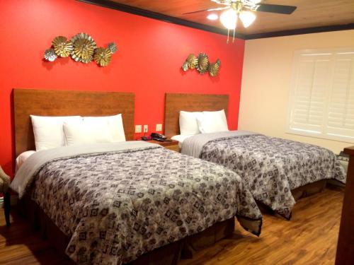 two beds in a hotel room with red walls at FairBridge Inn & Suites Gateway to Yosemite in Merced