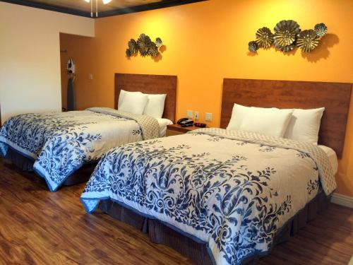 um quarto de hotel com duas camas com lençóis azuis e brancos em FairBridge Inn & Suites Gateway to Yosemite em Merced