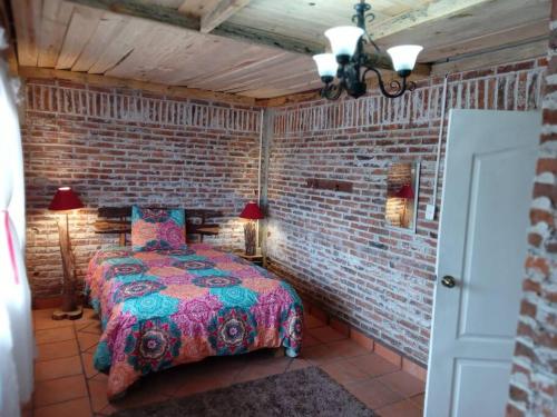 een slaapkamer met een bed in een bakstenen muur bij Hermosa cabaña en zacatlan puebla la escondida in Jicolapa