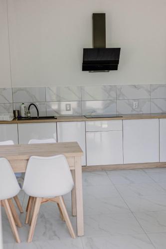 a kitchen with a wooden table and white cabinets at Apartamenty pod Jagodną in Spalona
