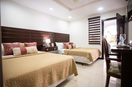 um quarto de hotel com duas camas e uma mesa e cadeiras em Casa Lolita Hotel-Boutique em Portoviejo