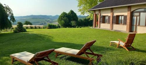 two chairs and a table on a lawn next to a house at Villa Pieve in Moncalvo