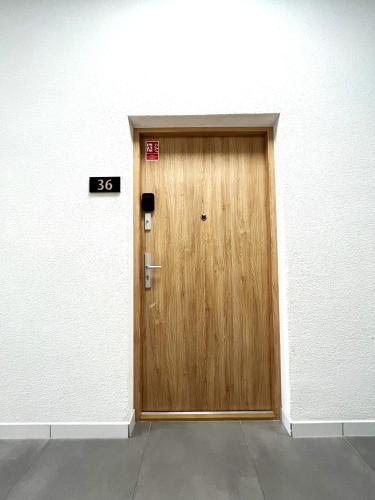 a wooden door in a white wall at Zarembowicza Apt 36 - Self Check-In 20h - Parking &Lift in Wrocław