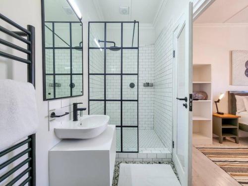 a white bathroom with a shower and a sink at Contemporary and Stylish Apartment in Observatory in Cape Town