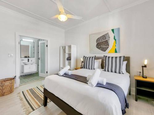 a bedroom with a large bed with a ceiling fan at Contemporary and Stylish Apartment in Observatory in Cape Town