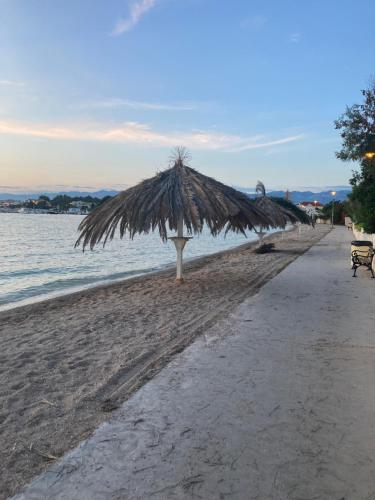 a beach with a straw umbrella and the water at Apartman Hmelina in Vrsi