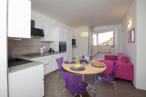 une cuisine et une salle à manger avec une table et des chaises violettes dans l'établissement Appartamento Casa vacanza Le Terrazze Via Parigi,23, à Castelsardo