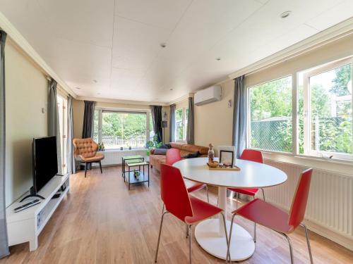 a living room with a table and chairs and a tv at Chalet in Grenspark Kalmhoutse Heide near Antwerp in Putte