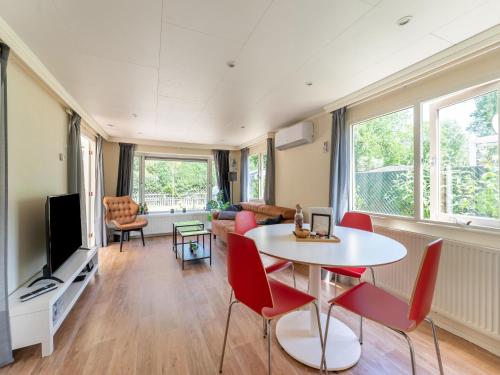 een woonkamer met een tafel en stoelen en een televisie bij Chalet in Grenspark Kalmhoutse Heide near Antwerp in Putte