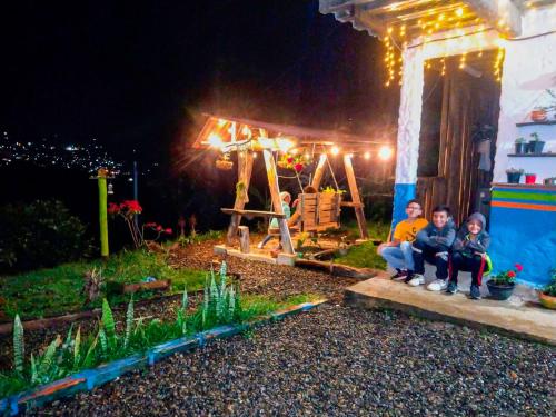 a group of people sitting in front of a house at night at Casa Viva Alojamiento Rural in Jardin