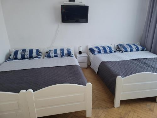 a bedroom with two beds and a tv on the wall at Pokoje Gościnne Galeon w Darłówku in Darłowo