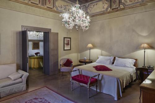 a bedroom with a large bed and a chandelier at Albergo Cappello in Ravenna