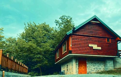 a small wooden house with a fence and trees at Log cabin 2 Merdovic in Mojkovac
