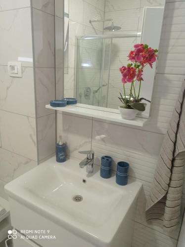 a bathroom sink with a vase of flowers on it at Apartman MORE Živogošće in Živogošće