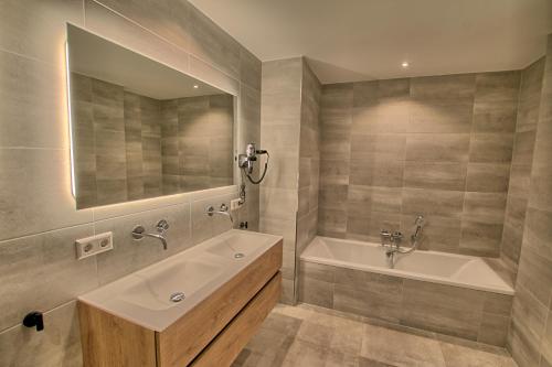 een badkamer met een wastafel, een bad en een spiegel bij Najade Resort Het Gooi in Eemnes