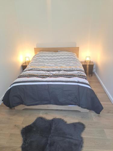 uma cama num quarto com um gato preto deitado no chão em Chez David em Cholet