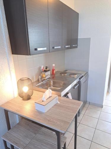 uma cozinha com um lavatório e uma mesa com um livro em Chez David em Cholet