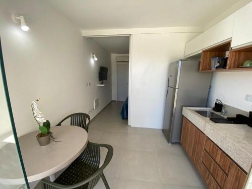 uma pequena cozinha com uma mesa e cadeiras e um lavatório em Flats em Salvador à 150m da praia em Salvador