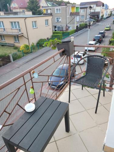 a balcony with a wooden bench and a bird feeder at Pokoje Gościnne Galeon w Darłówku in Darłowo