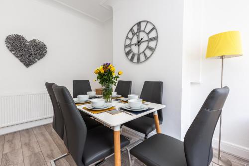 une salle à manger avec une table, des chaises et une horloge dans l'établissement Connaught House - Wi-Fi, Parking, Contractors, à Preston