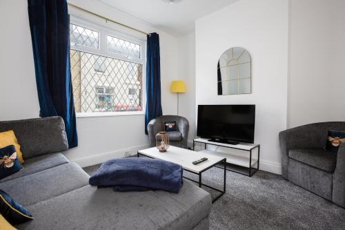 ein Wohnzimmer mit einem Sofa und einem TV in der Unterkunft Connaught House - Wi-Fi, Parking, Contractors in Preston