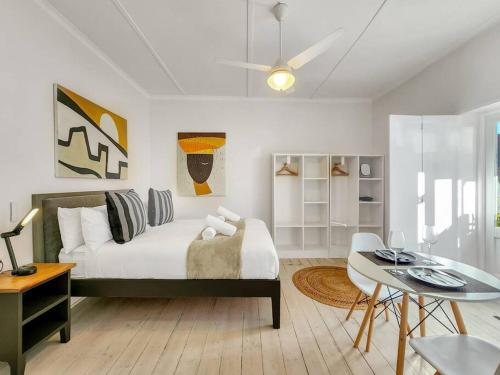 Visually Stunning apartment في كيب تاون: غرفة نوم بيضاء مع سرير وطاولة