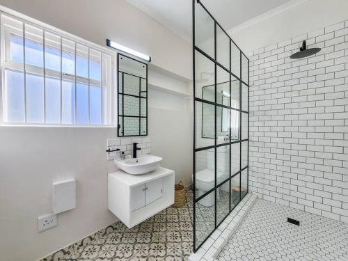 Visually Stunning apartment في كيب تاون: حمام أبيض مع حوض ومرآة
