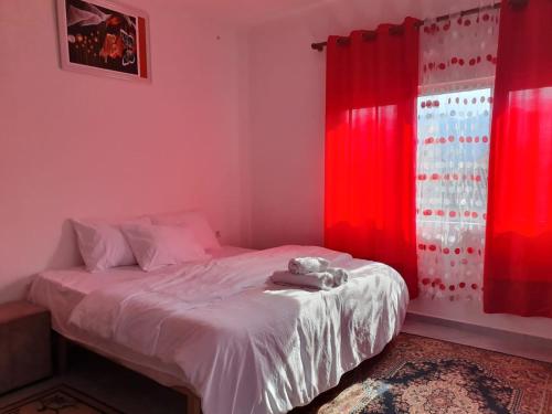 a bedroom with red curtains and a bed with a stuffed animal on it at Bar-Restaurant-Hotel-Familja in Klos