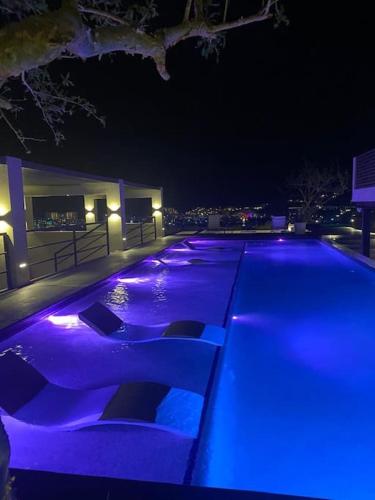 a swimming pool lit up at night with blue lights at Live! Departamento céntrico con asombroso Rooftop y Alberca in Cabo San Lucas