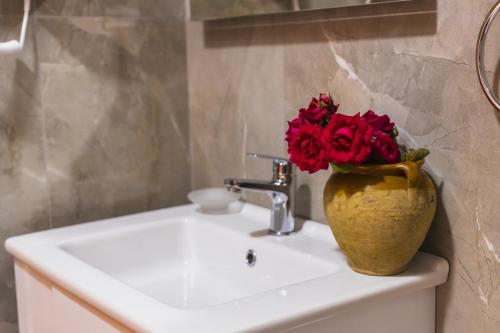 a vase filled with red roses sitting on top of a sink at Villa Porta Qeparo in Qeparo