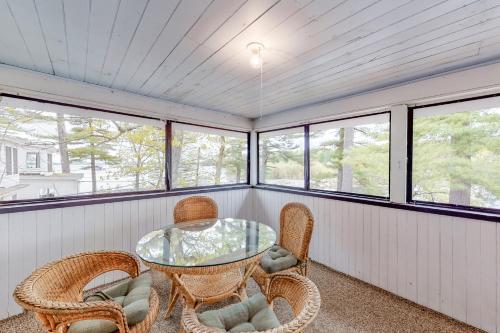 a screened in porch with a glass table and chairs at Rustic Lake Retreat in Standish