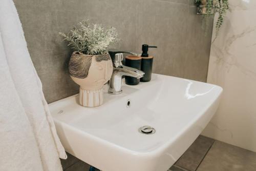 a bathroom sink with a vase with a plant on it at Sophia's Coastal Retreat in Korinos