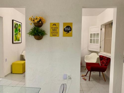a living room with a red chair and signs on the wall at casa de 4 quartos perto do Forte Orange Itamaracá in Itamaracá