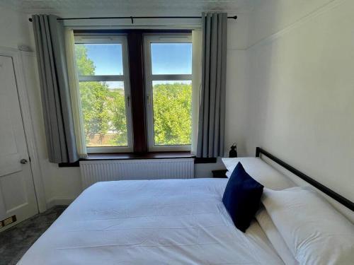 a bedroom with a white bed with a blue pillow at Large 2 bed near Glasgow Airport in Paisley
