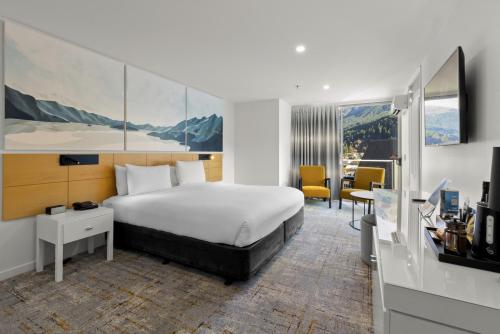 um quarto de hotel com uma cama, uma secretária e uma televisão em Scenic Suites Queenstown em Queenstown