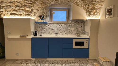 Le Conche Guest House - Casamassima في كاساماسيما: مطبخ به دواليب زرقاء ونافذة