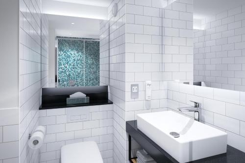 bagno bianco con lavandino e specchio di Holiday Inn Dijon Sud - Longvic, an IHG Hotel a Digione