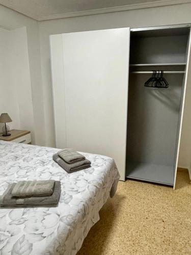 a bedroom with a bed and a closet with towels on it at Sol y playa in Puerto de Sagunto