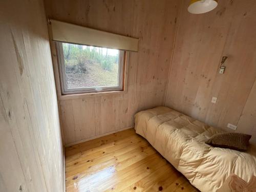 a bed in a room with a window at Cabaña Icalma, ahora con Tinaja in Curacautín
