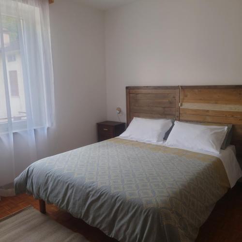 1 dormitorio con 1 cama con cabecero de madera y ventana en appartamento 'Il glicine' en Valli del Pasubio