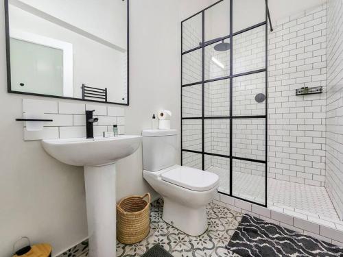 y baño con aseo, lavabo y ducha. en Spacious 2 BR Apartment In Obz, en Ciudad del Cabo