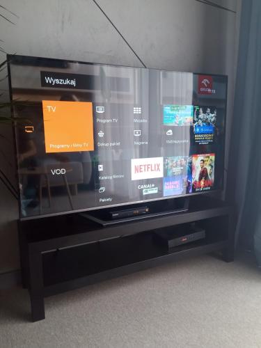 a flat screen tv sitting on top of a entertainment center at Wroclove Airport Loft in Wrocław