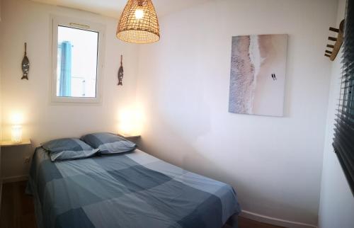 - une chambre avec un lit et une lampe pendant dans l'établissement Appartement avec piscine et garage proche plage et commerces, à La Seyne-sur-Mer
