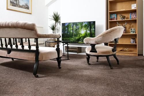a living room with two chairs and a television at The Water Works Cottage in London