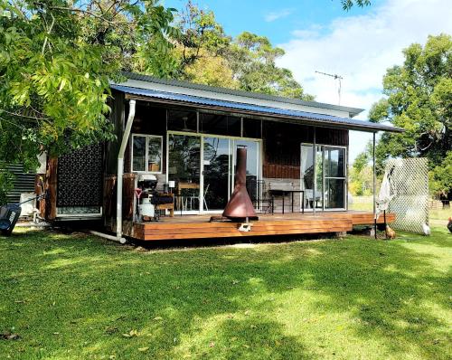 a small house with a large deck with a yard at Rusty's Hideaway - Adorable tiny house on a beautiful farm in Moorland