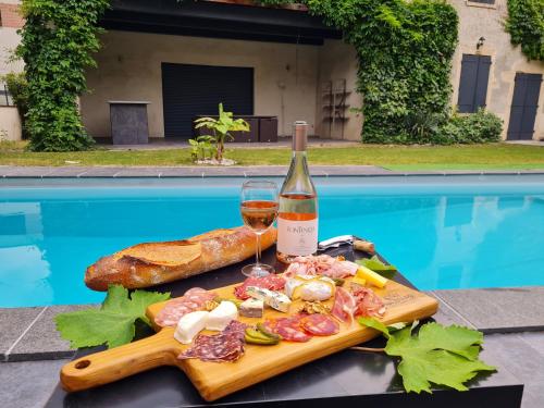 a plate of food and a bottle of wine next to a swimming pool at Lyon Faubourg - Saint Priest in Saint-Priest