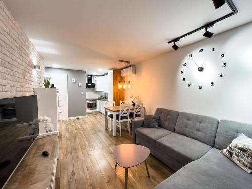 uma sala de estar com um sofá e um relógio na parede em Ul SZOPY 2 APARTAMENTY ZRESETUJ SIĘ W GDAŃSKU em Gdansk